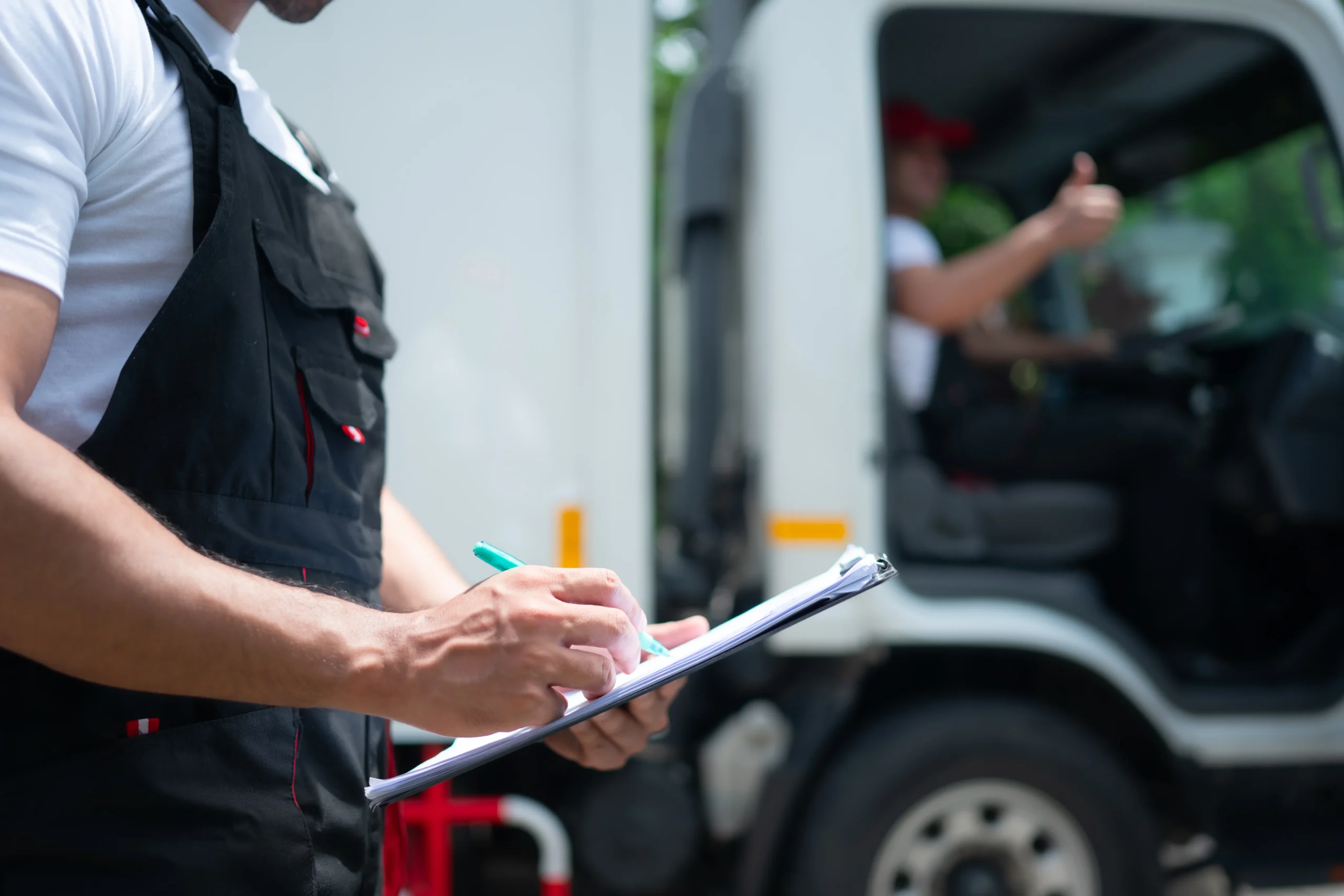 Logistics worker inspecting truck with clipboard during freight check Logistics worker inspecting truck with clipboard during freight check