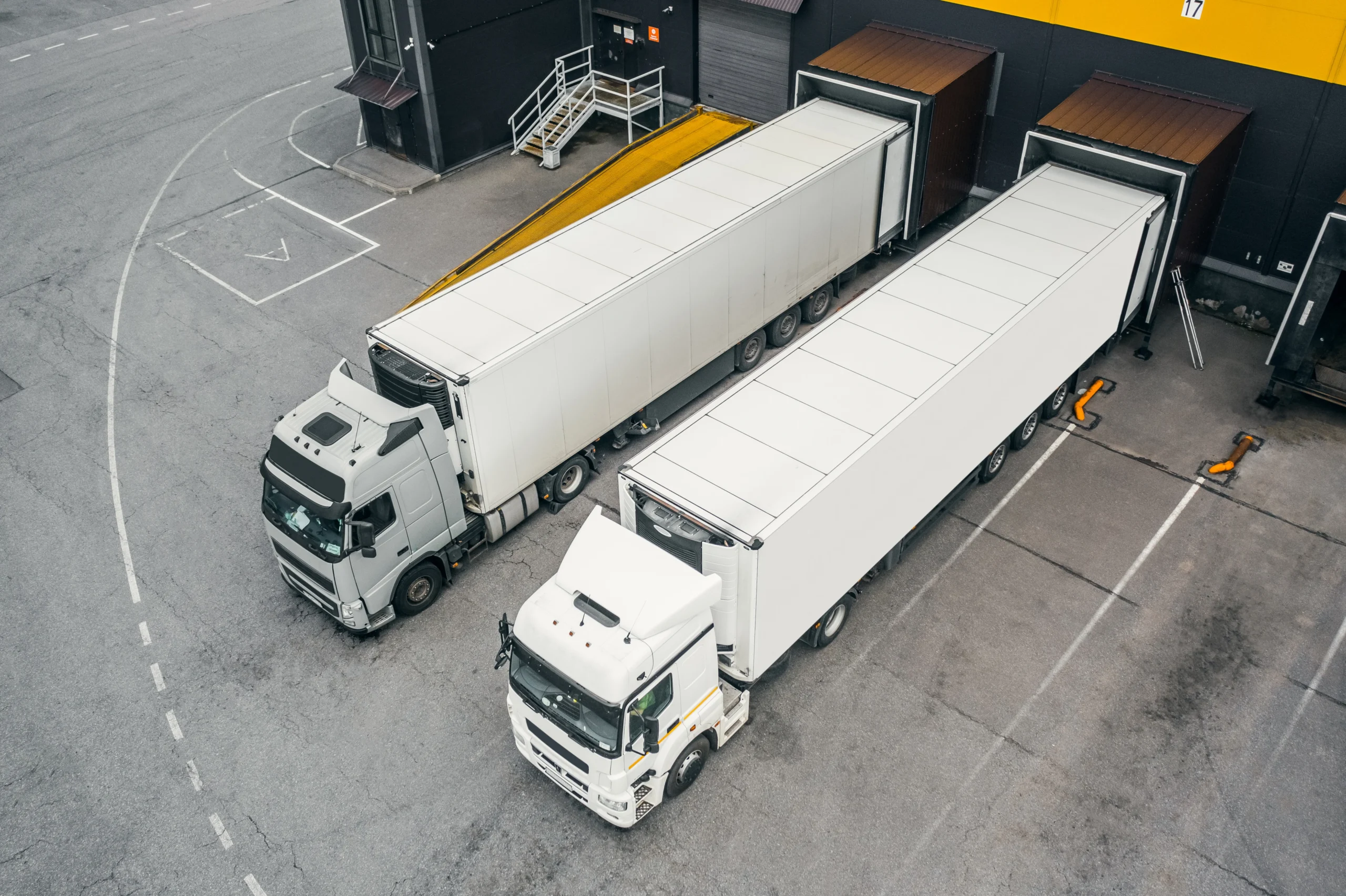 Two semi trucks parked at warehouse loading dock from aerial view Two semi trucks parked at warehouse loading dock from aerial view